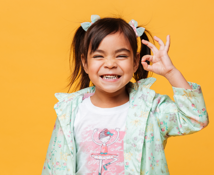 Petite fille souriante faisant un signe OK de la main